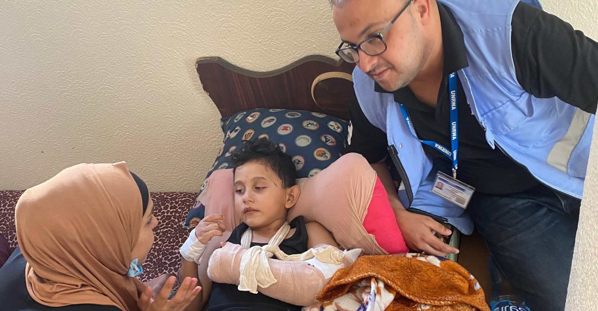 Ein kleiner verletzter Junge liegt in einem Bett in Gaza. Er hat einen eingebundenen Arm und viele Kratzer im Gesicht.