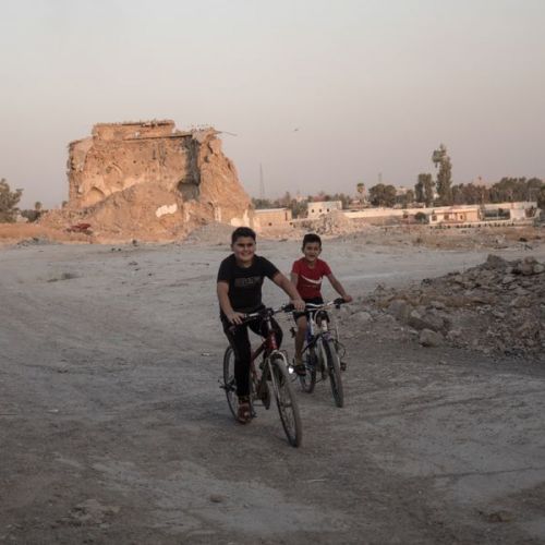 Zwei Jungen auf Fahrrädern inmitten von zerstörten Gebäuden