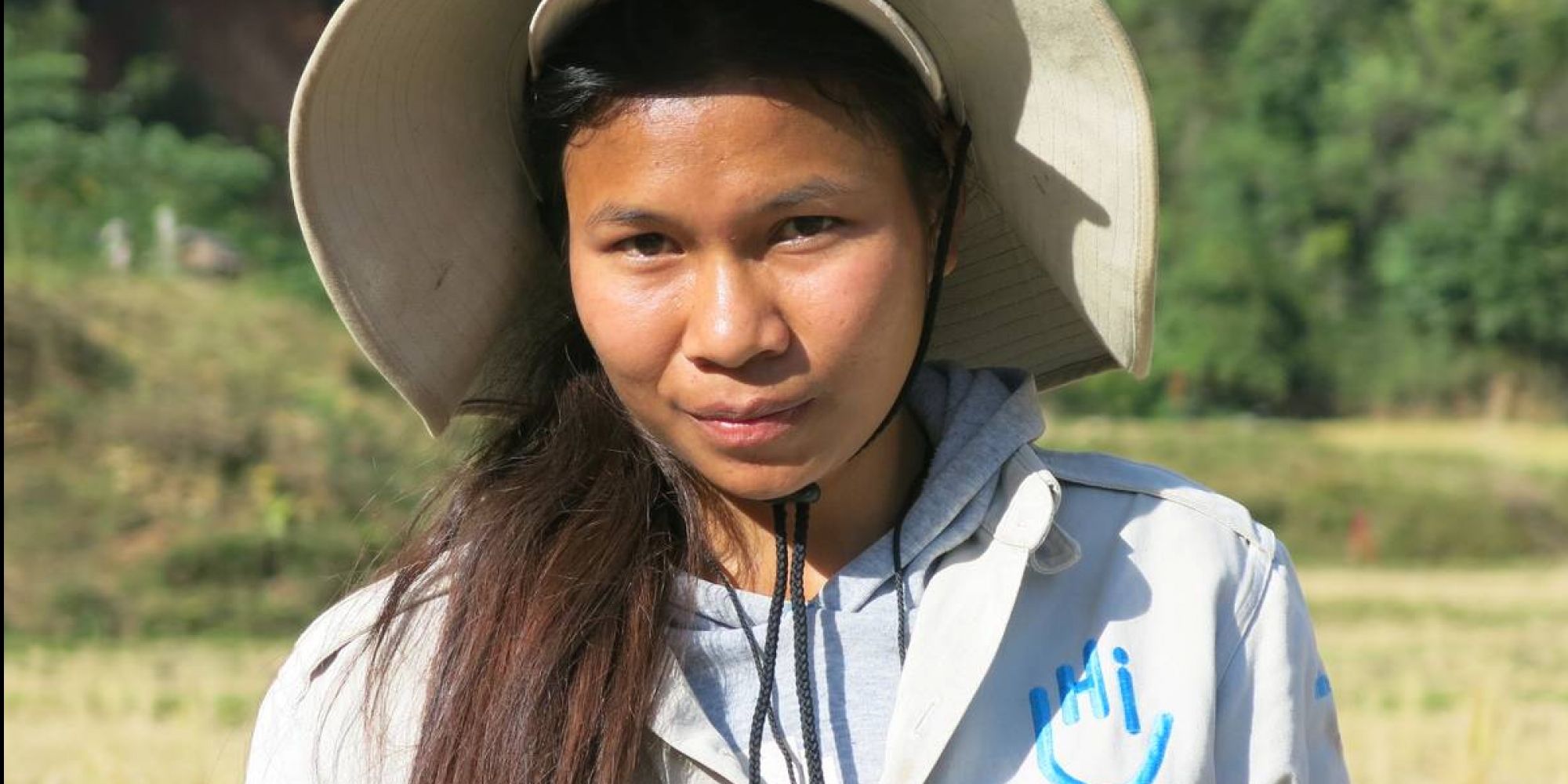 Eine junge Frau aus Laos. sie trägt eine HI-Uniform und einen breiten Sonnenhut