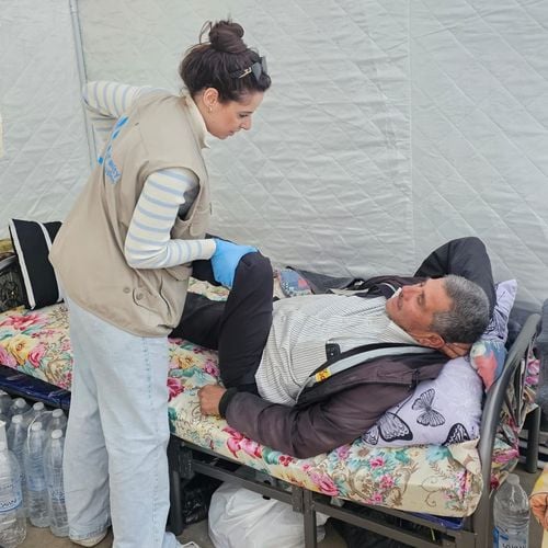 Eine HI-Physiotherapeutin behandelt einen verletzten Mann auf einer Liege