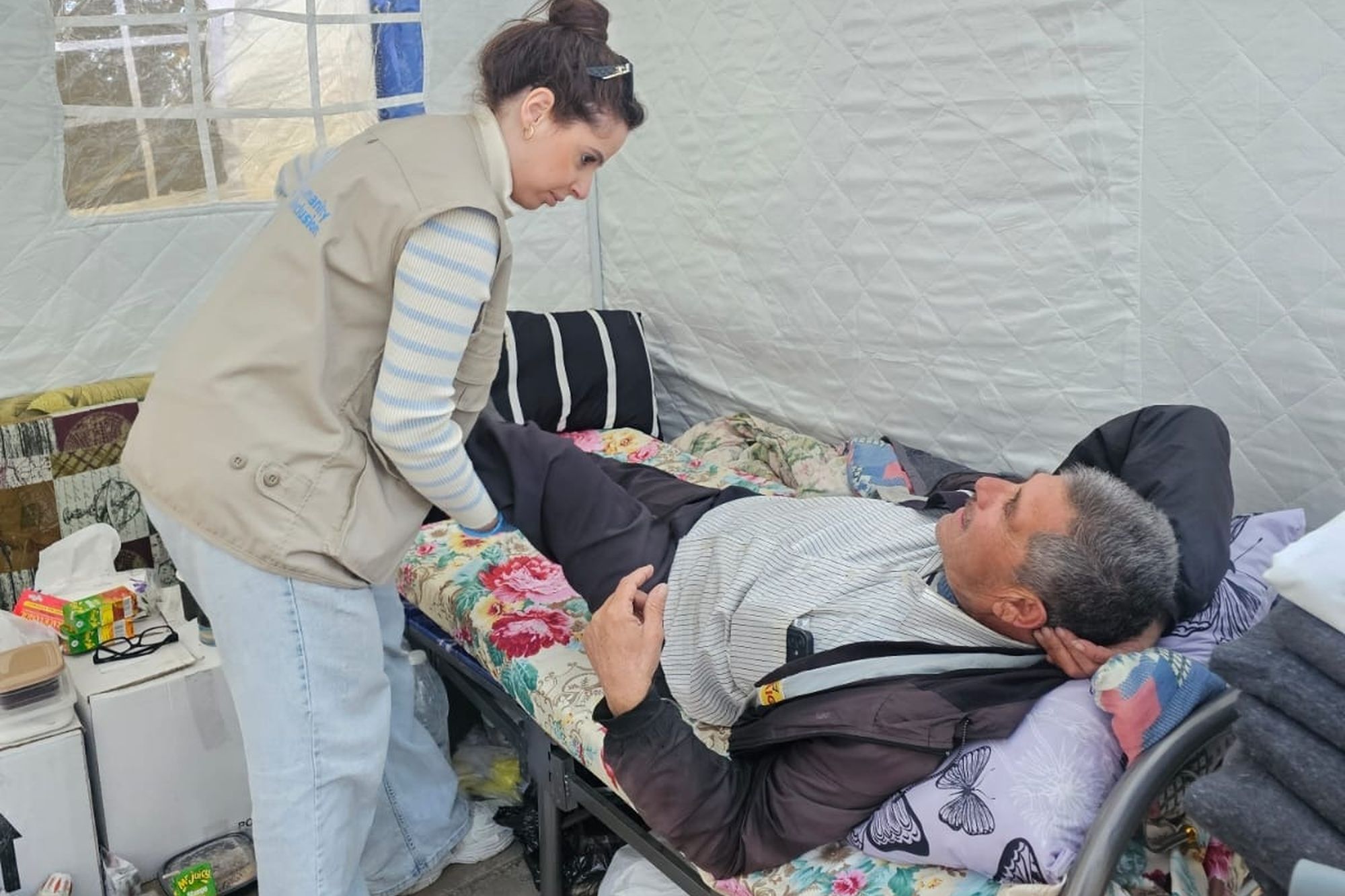 Eine HI-Physiotherapeutin behandelt einen verletzten Mann auf einer Liege