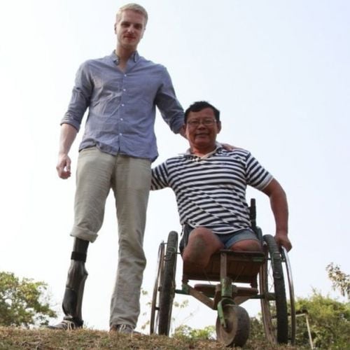 Zwei Männer nebeneinander. Ener hat ein künstliches Bein, er steht neben dem anderen Mann, der in einem Rollstuhl sitzt.