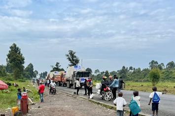 Viele Menschen stehen auf einer belebten Straße um zwei Transporter von HI