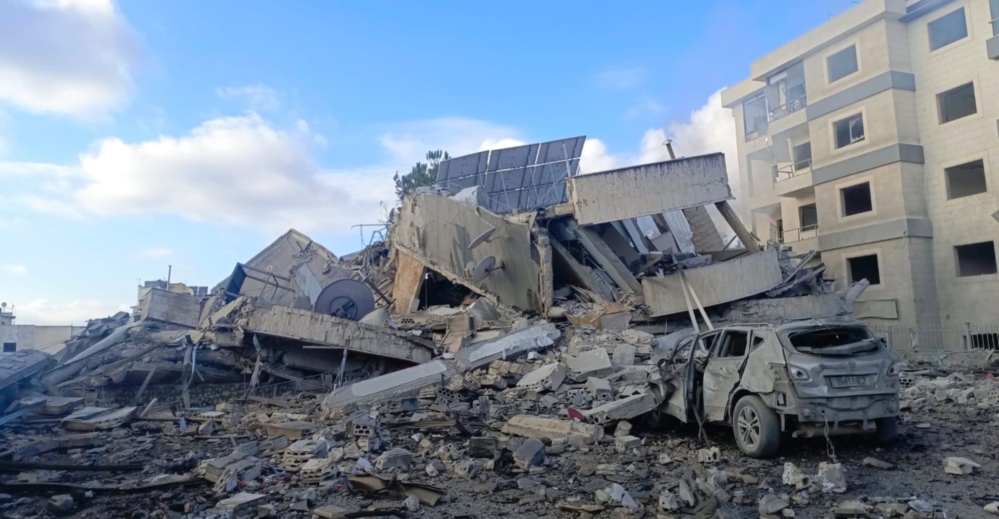 Ein zerstörtes Auto liegt unter einem eingestürzten Gebäude