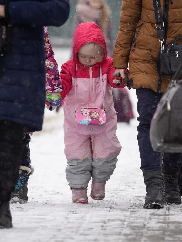 Flüchtlinge im Winter, eine kleines Mädchen geht an der Hand seiner Eltern