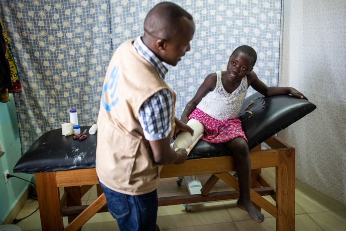 Ein Mädchen aus der Demokratischen Republik Kongo auf einer Liege mit ihrem Physiotherapeuten von Handicap International. Durch einen Rebellenangriff verlor sie ihr rechtes Bein.