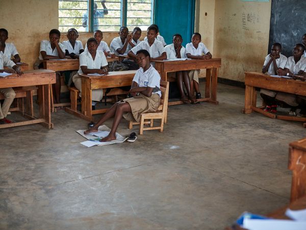 Sarah sitzt in der Schule in Ruanda und schreibt mit ihren Füßen. Sie hat eine Mehrfachbehinderung durch Sauerstoffmangel bei der Geburt. © N. Thomas / HI