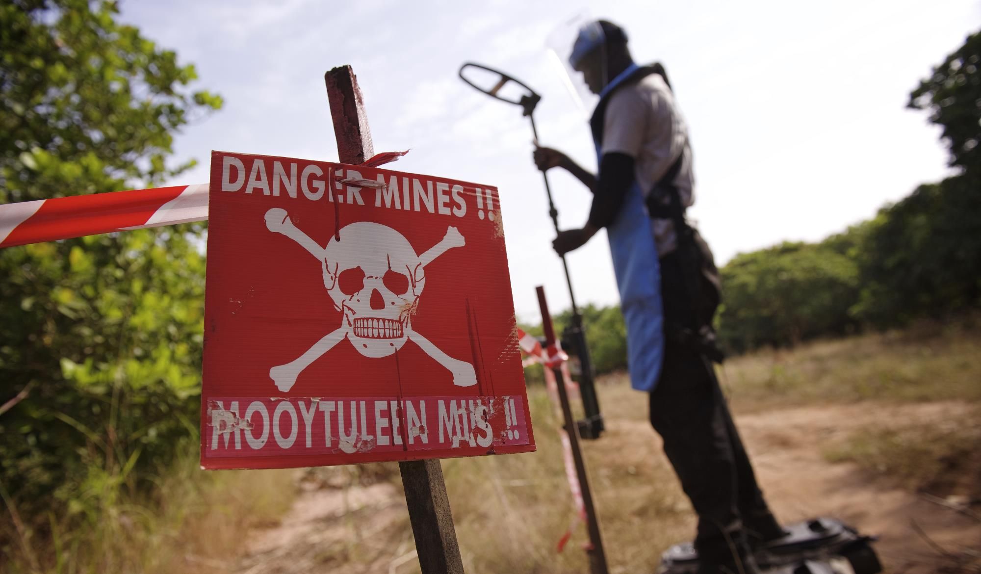 Ein großes rotes Schild im Vordergrund zeigt einen Totenkopf und die Aufschrift 