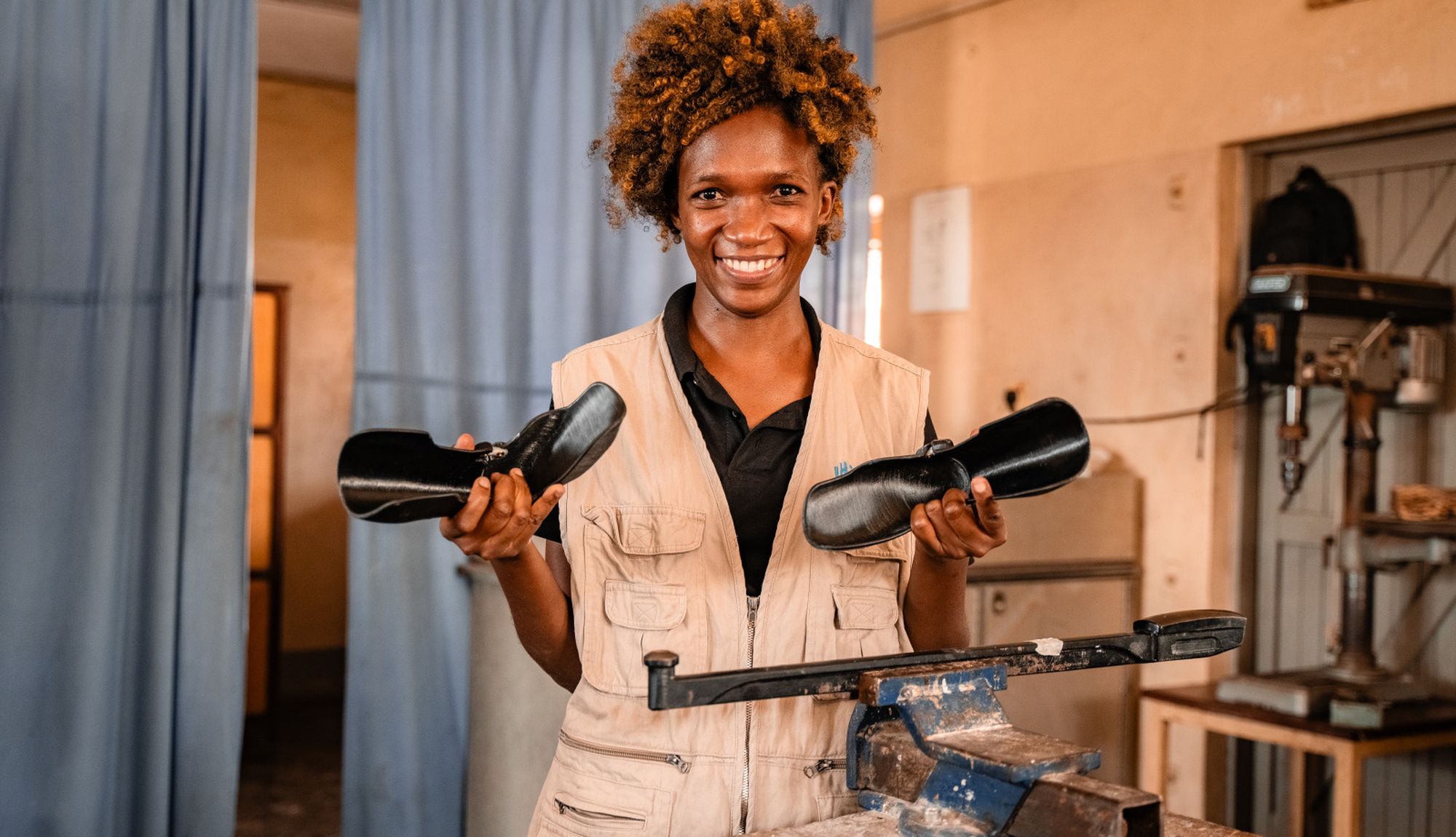 Frau aus Uganda hält 2 Orthesen aus dem 3D-Drucker in der Hand