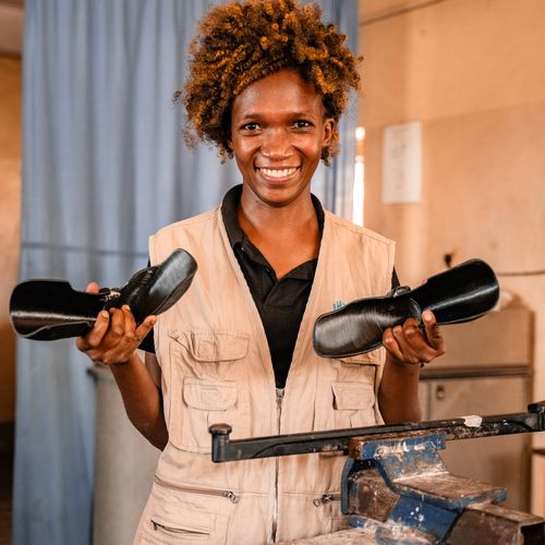 Frau aus Uganda hält 2 Orthesen aus dem 3D-Drucker in der Hand