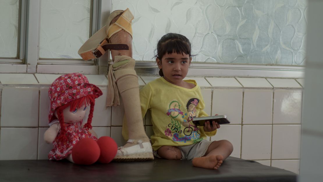 Die 4-jährige Hala aus dem Jemen sitzt auf einer Liege. Ihr fehlt das rechte Bein. Eine Prothese und ein Kuscheltier liegen neben ihr.