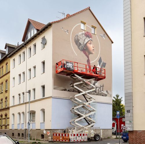 Das Graffiti ist zeigt ein junges Mädchen zwischen den Trümmern