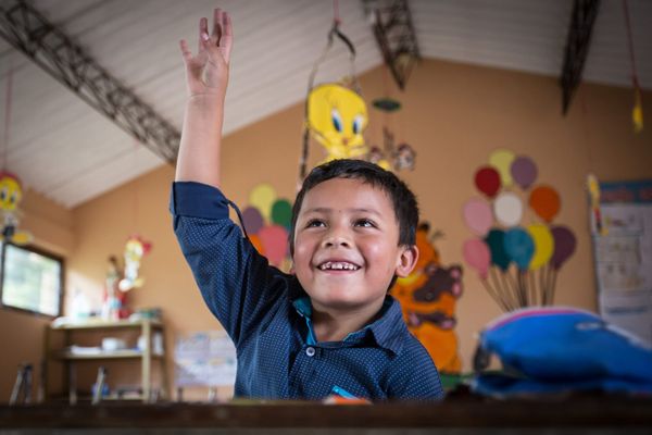Juan José aus Kolumbien sitzt im Klassenzimmer und hebt die Hand. Er musste amputiert werden und kann dank einer Prothese zur Schule gehen.