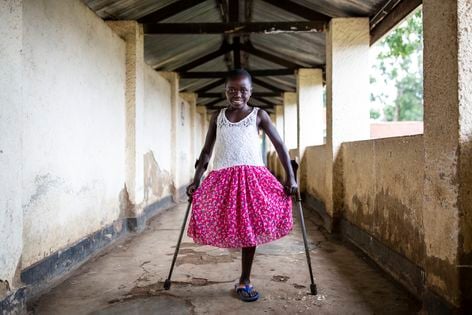 Kelvine aus der Demokratischen Republik Kongo steht auf Krücken in einem Gang. Ihr fehlt das rechte Bein.