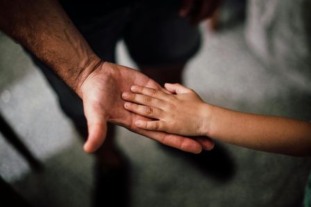 Eine Kinderhand liegt auf einer Hand eines Erwachsenen