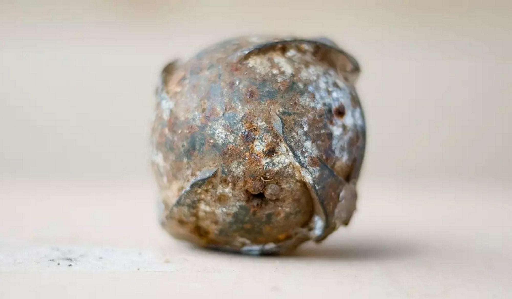 Eine einzelne Streubombe, sie sieht aus wie ein unregelmäßiger Ball aus Metall.