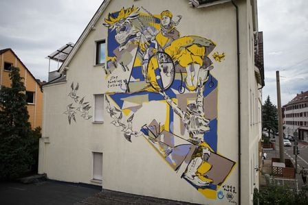Das Wandbild zeigt eine abstrakte Interpretation von Picassos Guernica mit einem Mädchen im Rollstuhl, der an Ketten hängt.