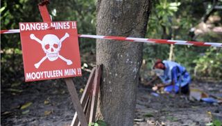 Minen-Warnschild und Entminer im Hintergrund; }}