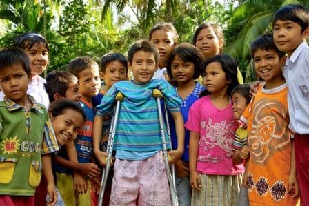 Asiatische Kindergruppe mit einem Jungen auf Krücken in der Mitte