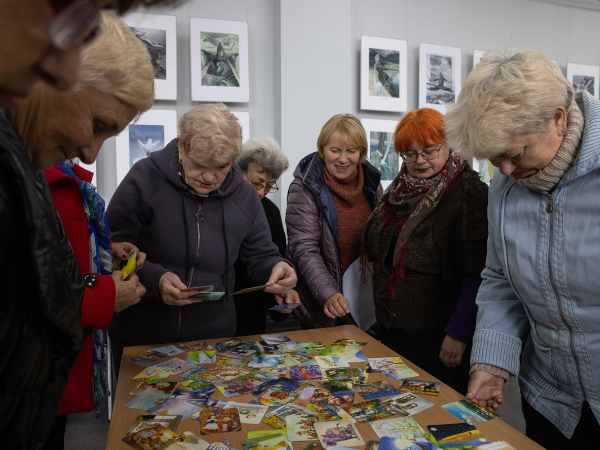 Ältere Ukrainerinnen stehen um einen Tisch und schauen sich Karten an, die darauf verteilt sind. 