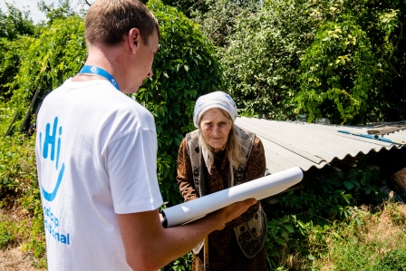Frau hält ein Schild zur Gefahrenaufklärung in die Höhe vor einer Menschengruppe