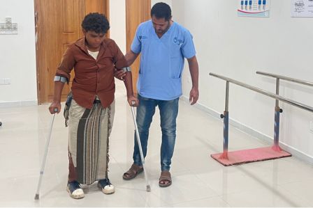 Junger Mann mit amputierten Bein sitzt vor seiner Hütte. 