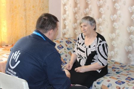 Nahaufnahme von lachenden älteren Frauen im Vordergrund ist angeschnitten eine kleine Karte mit einem Smiley zu sehen.