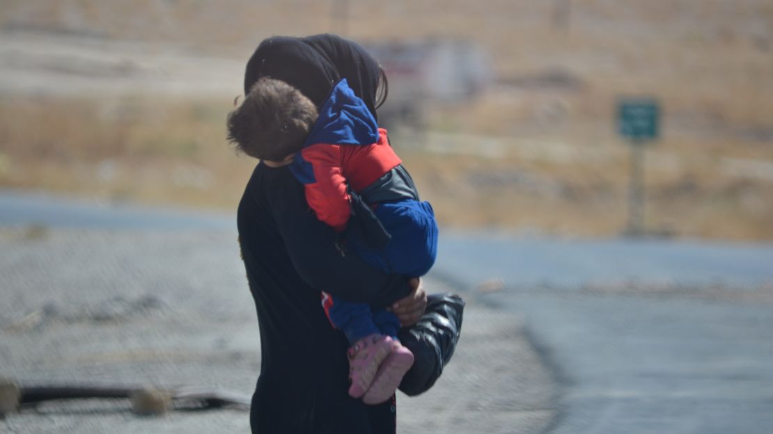 Eine Mutter trägt ihr Kind auf dem Arm. Die Gesichter sind nicht zu sehen. Sie leben in einem Camp für Binnenflüchtlinge in Syrien.