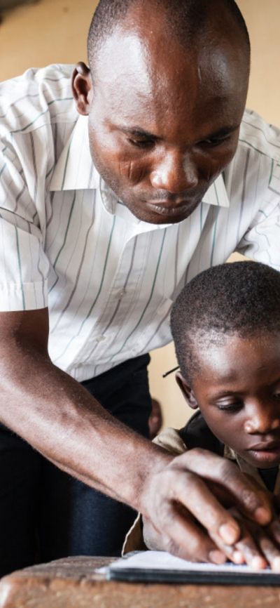Trésor, 7 Jahre alt, hat eine Sehbehinderung. Auf diesem Bild lernt er mit einem Lehrerer die Braille-Schrift.