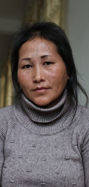 Portrait von Mrs Xoua, einer Frau mittleren Alters. Sie schaut neutral in die Kamera und hat den Kopf leicht geneigt.